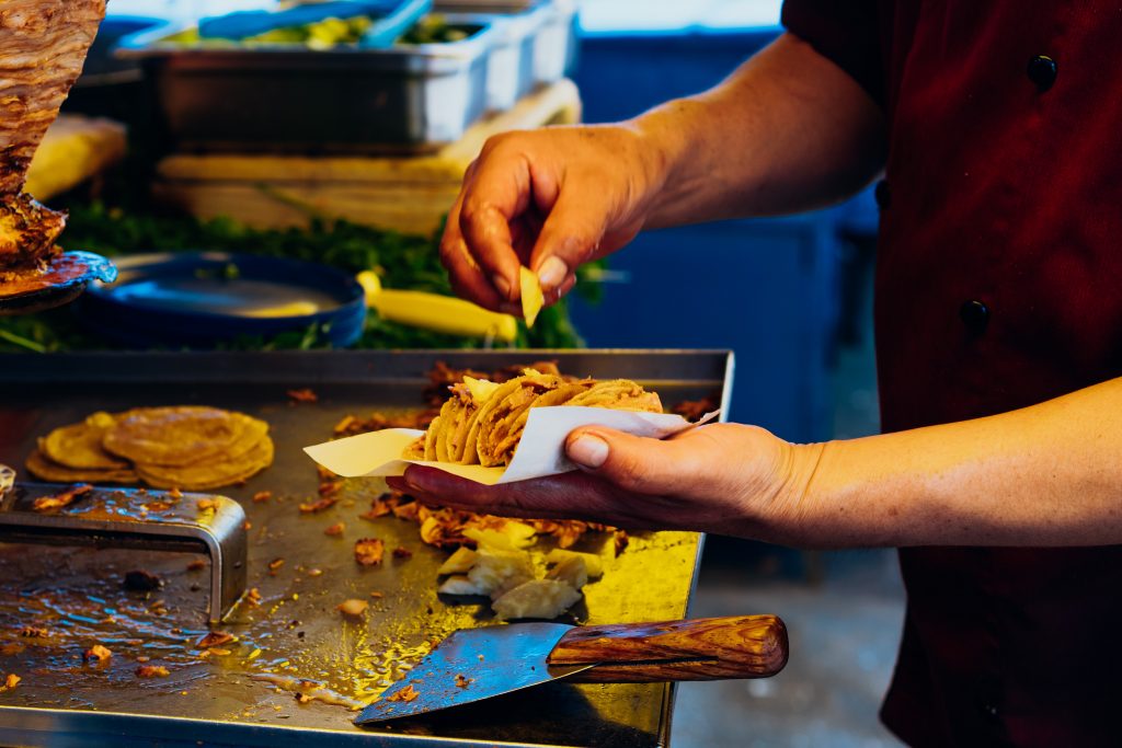 Photo of man preparing taco illustrates blog: "Do Tacos Al Pastor Have Pineapple?"