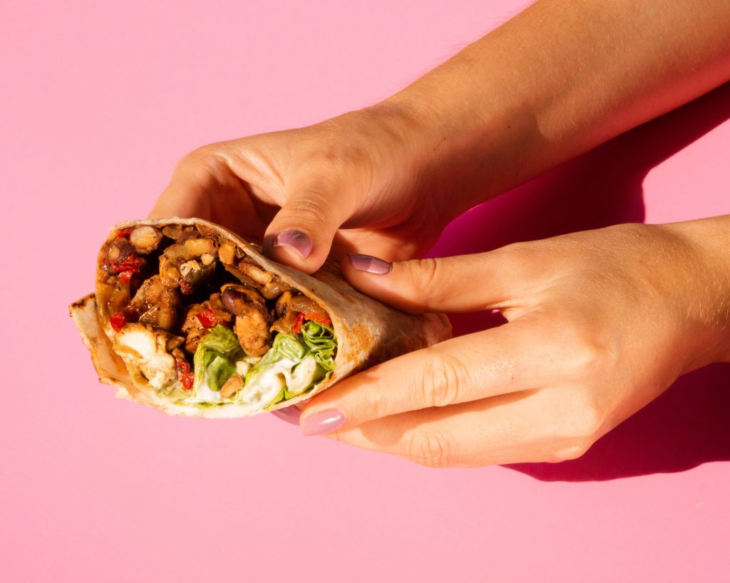 Photo of woman holding burrito illustrates blog: "Why Are Burritos Called Burritos?"