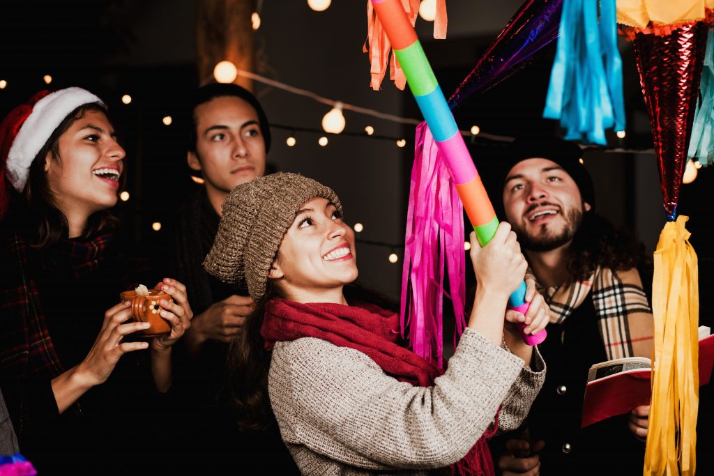Photo of friends breaking a pinata illustrates blog: "4 Mexican Christmas Traditions You Need to Know"