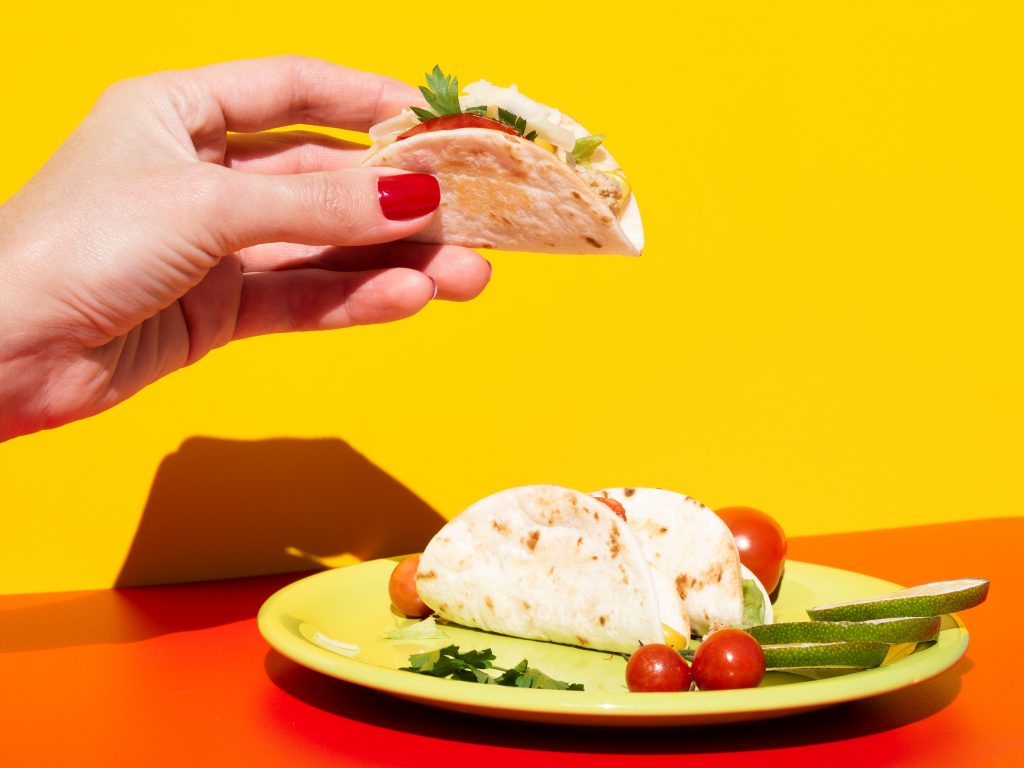 Closeup of woman holding taco illustrates blog "Are Tacos Finger Food?"