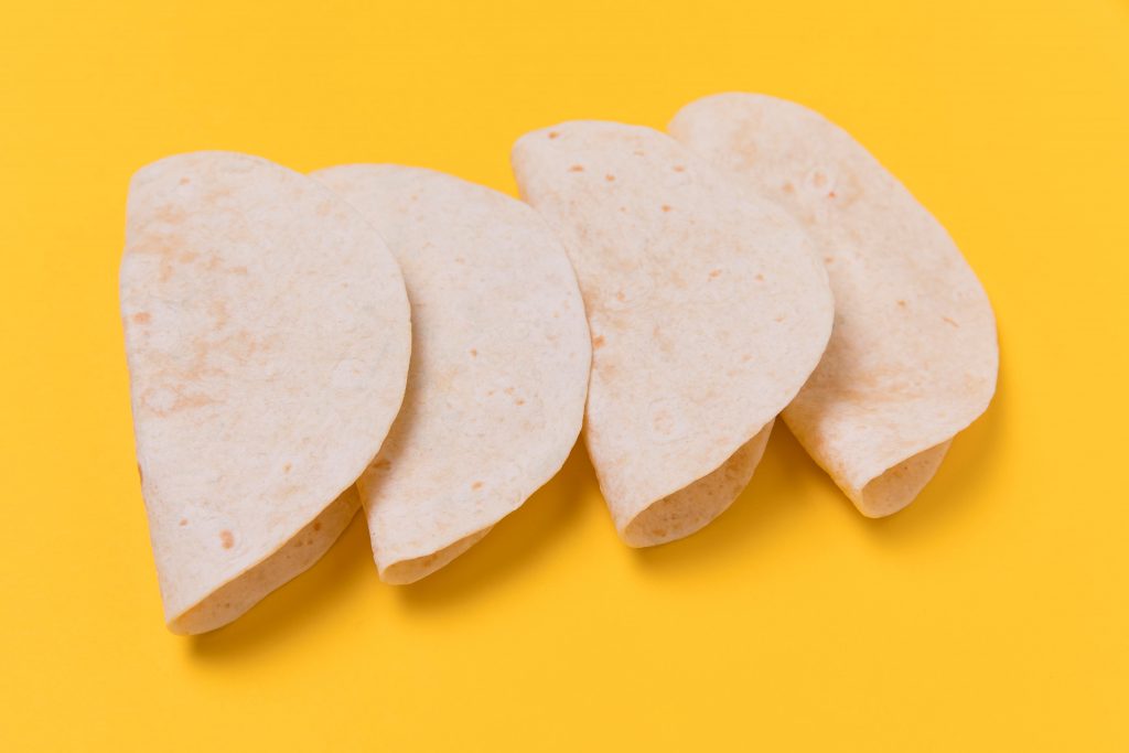 Four tortillas on yellow background illustrate blog "Are Tortillas Mexican or Spanish?"