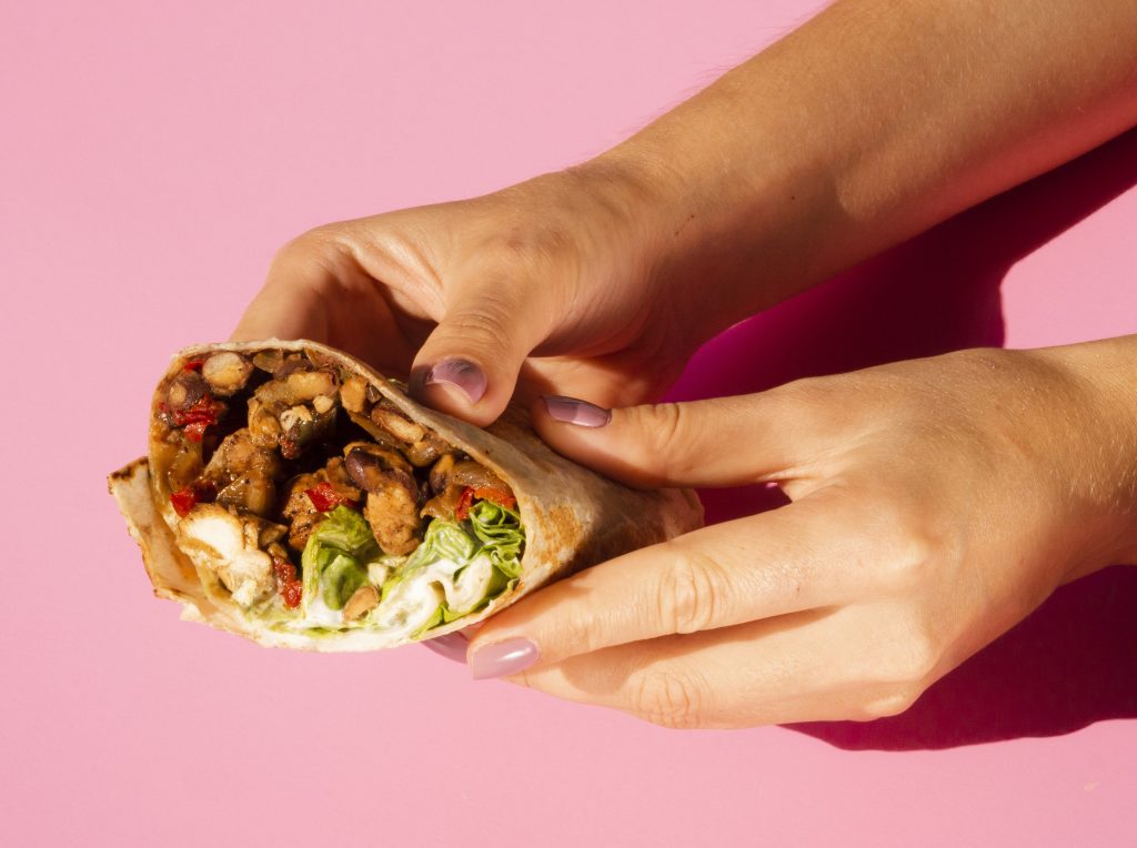 Closeup of woman holding burrito illustrates blog "Are Burritos Mexican?"